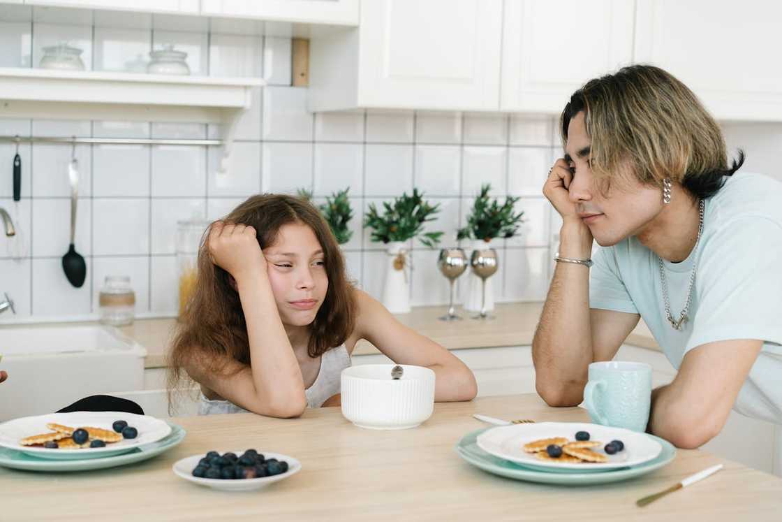 A father and daughter sitting at a breakfast table while talking.