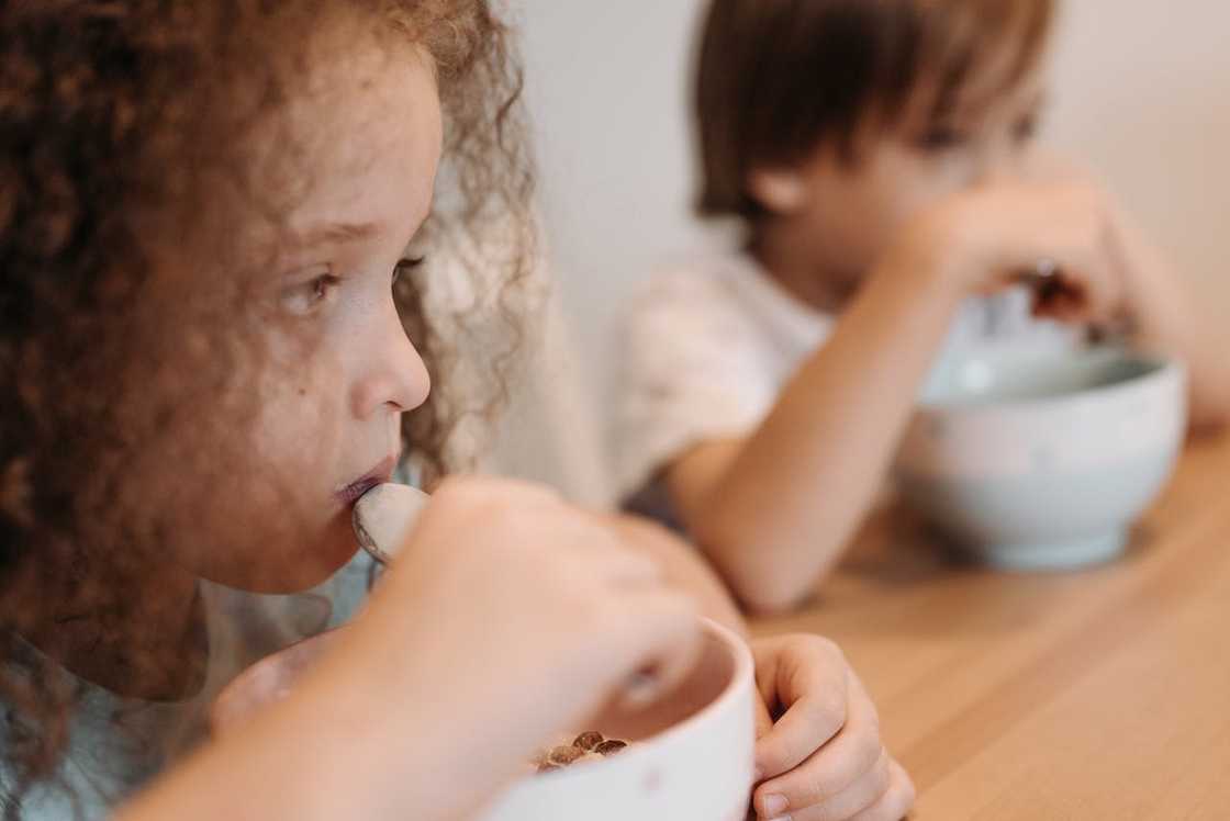 Two children eating from bowls. Two children eating from bowls.
