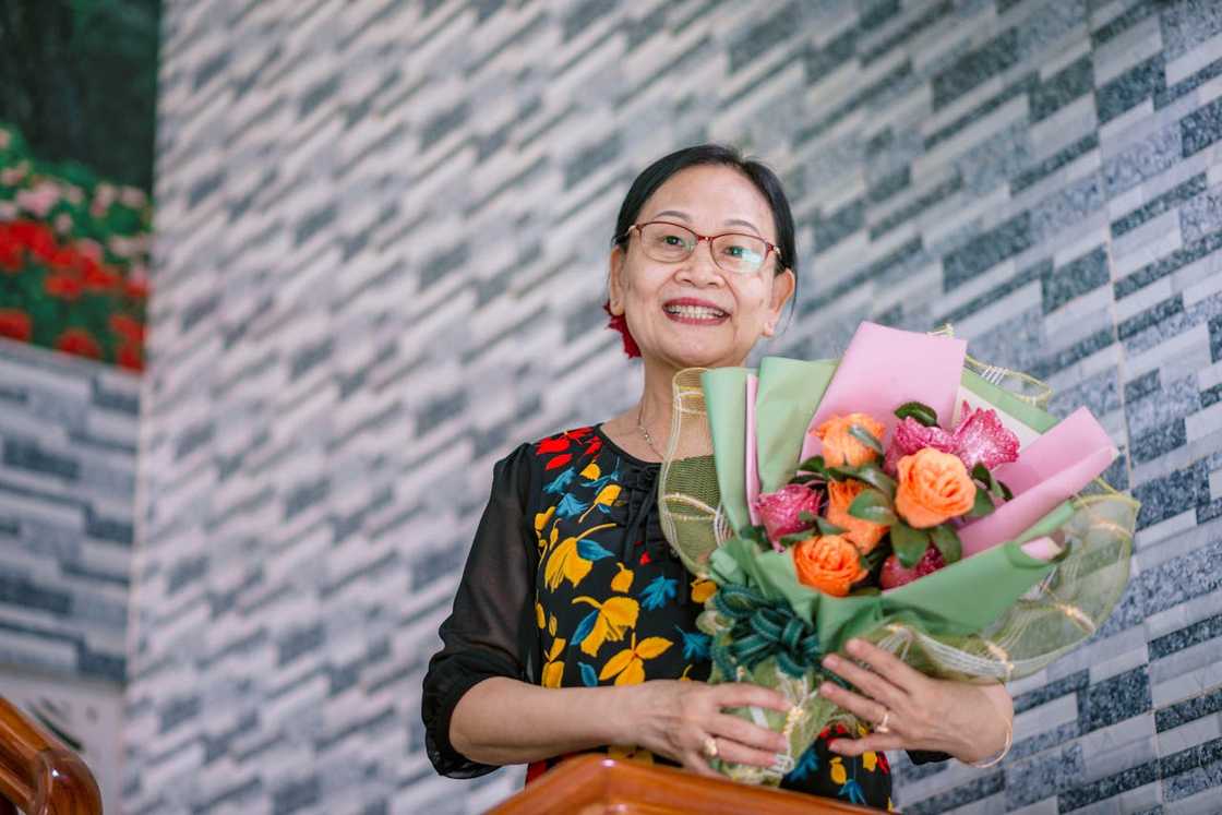 A woman smiles and holds a vibrant flower bouquet.