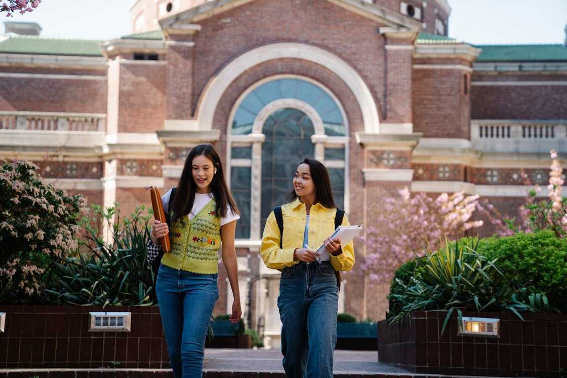 Two young women walk in the university compounds. Two young women walk in the university compounds.
