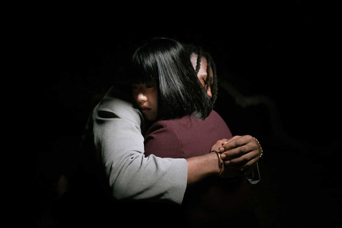 A woman hugging a minor in a dark room A woman hugging a minor in a dark room