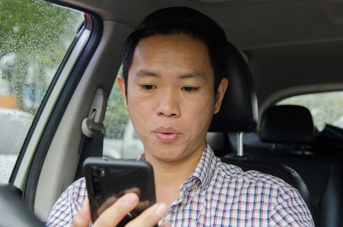 A man looking at smart phone in a car. A man looking at smart phone in a car.