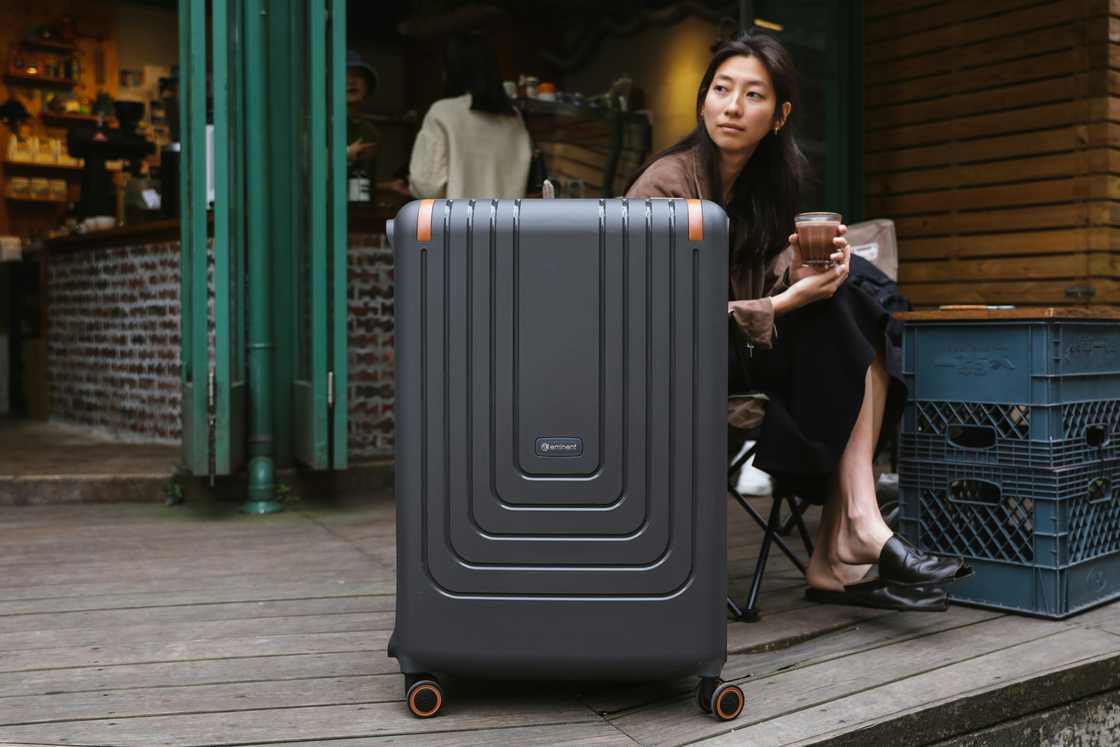 A young woman with a suitcase in front of a gate. For illustrative purposes only. A young woman with a suitcase in front of a gate. For illustrative purposes only.