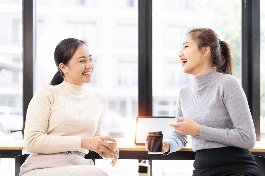 Beautiful women smiling and talking together, sitting on a counter table in a coffee shop.