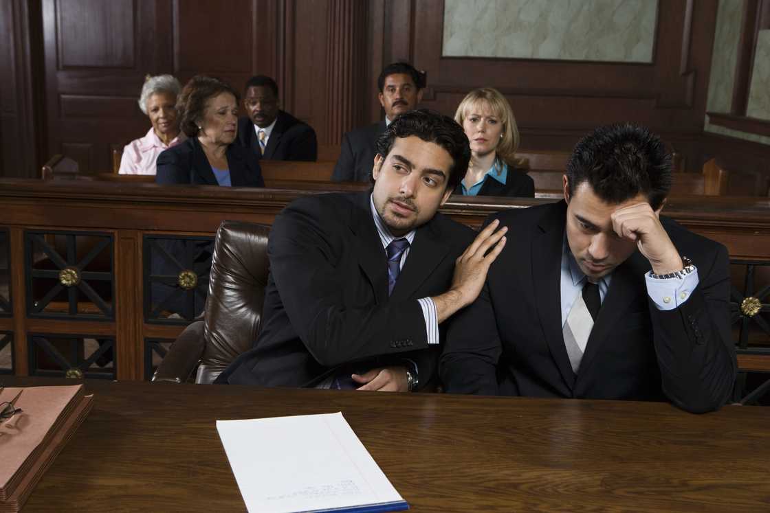Lawyer comforts a distressed defendant during a courtroom proceeding.