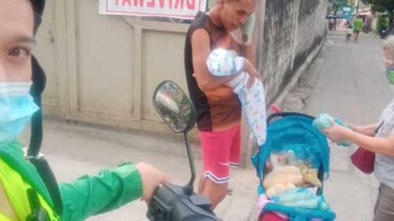Ulirang ama, karga-karga ang anak na sanggol habang inilalako ang hilaw na mais